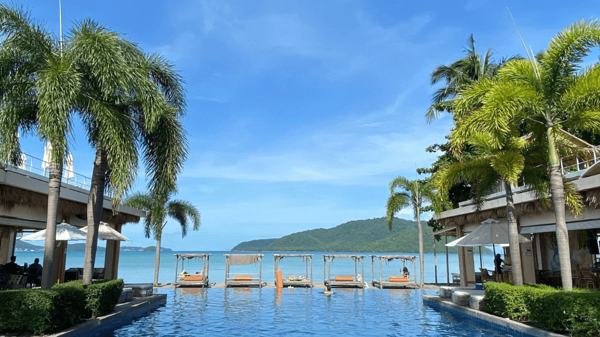 Swimming Pool with Palmtrees, Sea, and Sunbeds in Phuket, Thailand