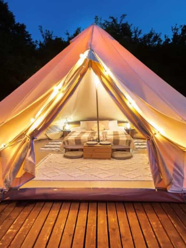 tent interior exterior lamps wooden chairs glamping forest night Stock
