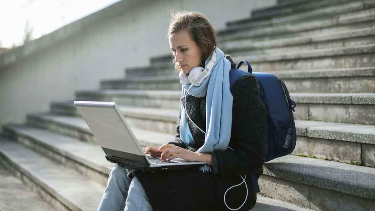 Person-With-Backpack-and-Laptop-Sitting-on-Stairs-Stock