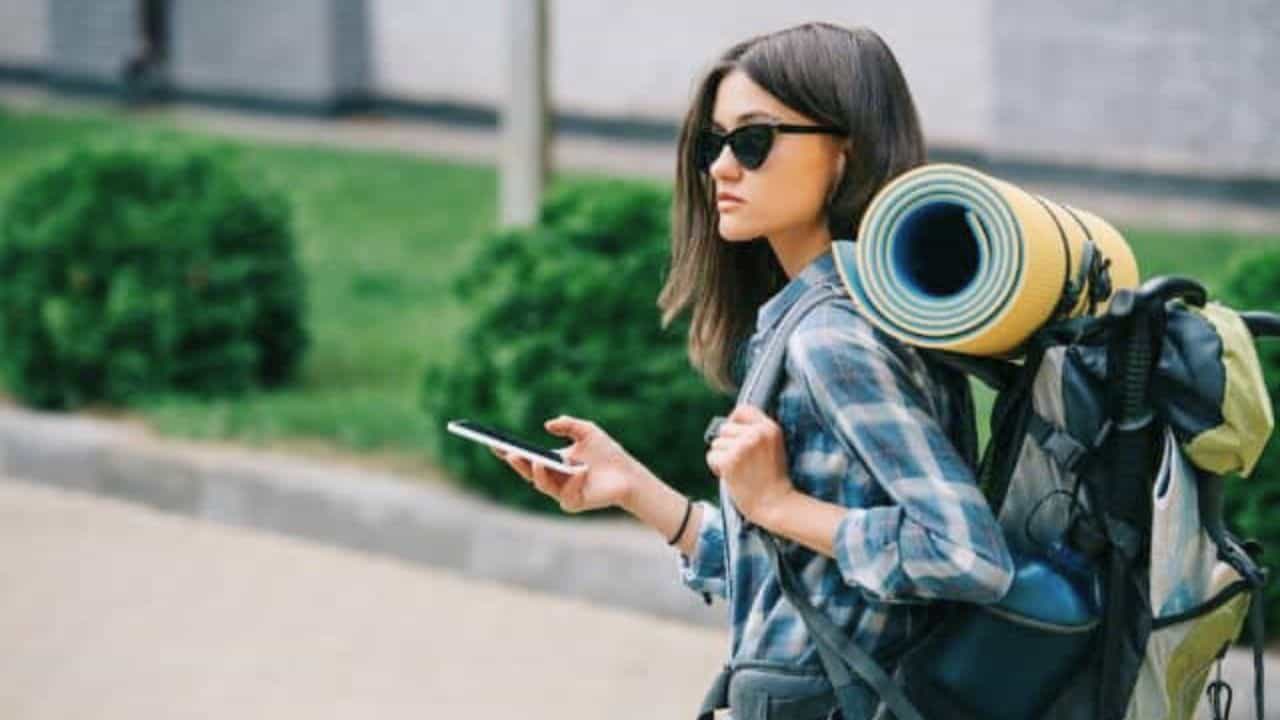 Young female backpacker in sunglasses stock
