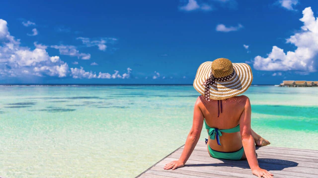 Young slim woman laying on pier, tropical beach stock