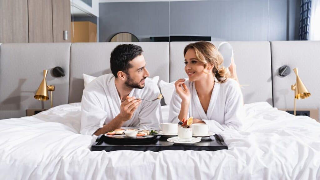 Couple Having Breakfast on Tray on Hotel Bed Stock