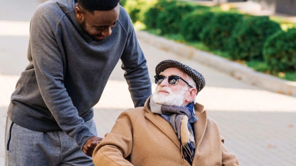 Senior Disabled Man in Wheelchair and African American Man Talking on Street Stock