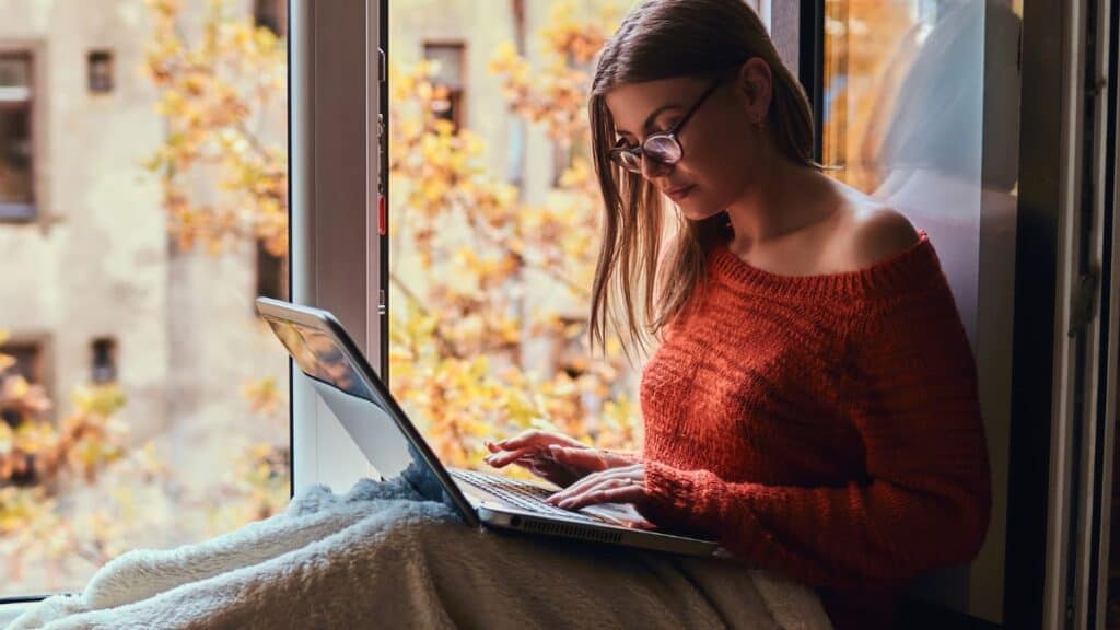 Writer typing on her computer by the window